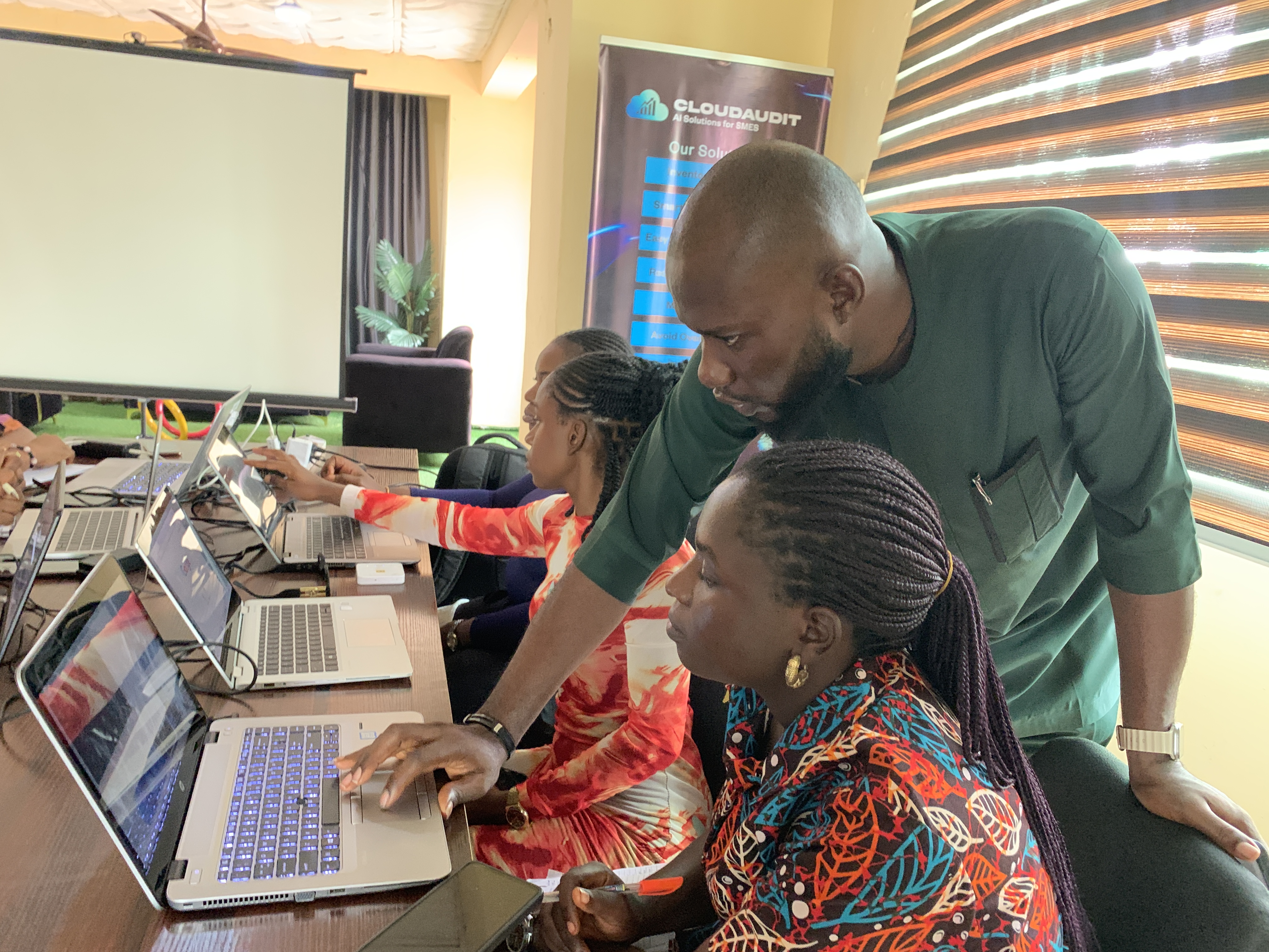 Group of learners gathered around a laptop during a training session
